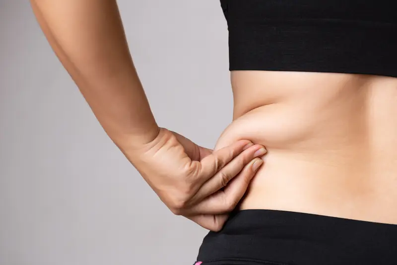 Mujer pellizca la grasa localizada de su abdomen