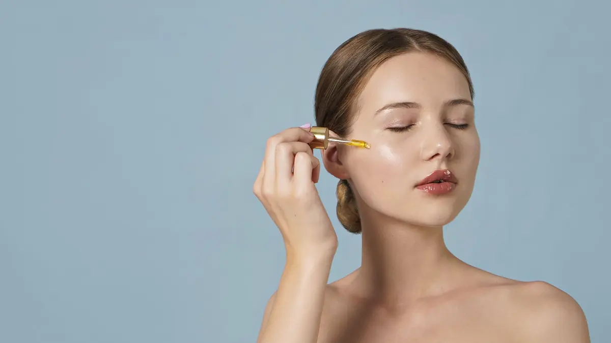 Mujer aplicándose un sérum con los ojos cerrados