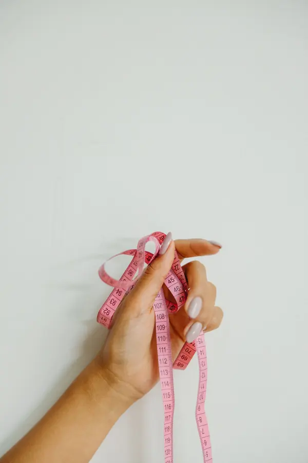Mano con una cinta métrica rosa