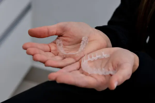 Manos sosteniendo alineadores transparentes