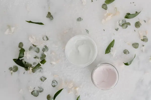 Tarros de crema con hojas sobre mármol