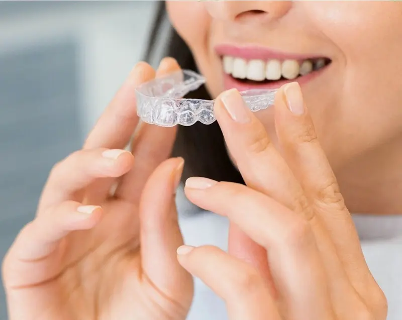 Mujer sonriente colocándose un alineador transparente