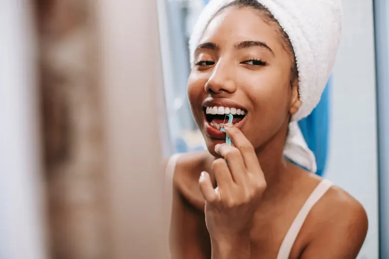 Mujer sonriente cuida sus encías con hilo dental