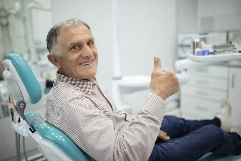 Odontóloga explica a una paciente un implante dental con un modelo de mandíbula