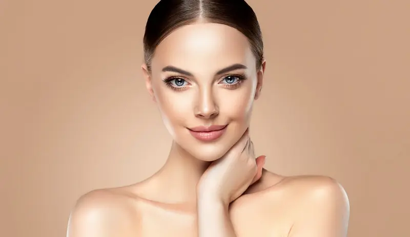 Mujer sonriente con la piel luminosa sobre fondo beige